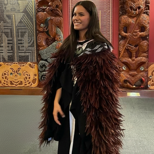 A contemporary Māori korowai featuring a contemporary kahukiwi design with brown feathers on a female.