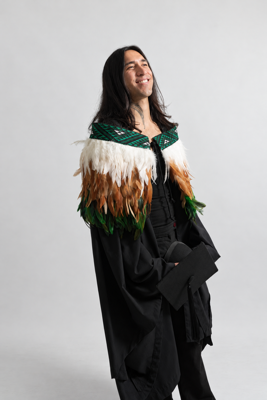 Model smiling while wearing the Ngāhere Green contemporary adult korowai.