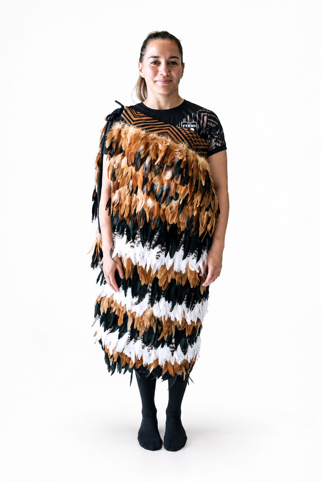 Api wearing a full-length custom brown, black and white korowai against a white background.