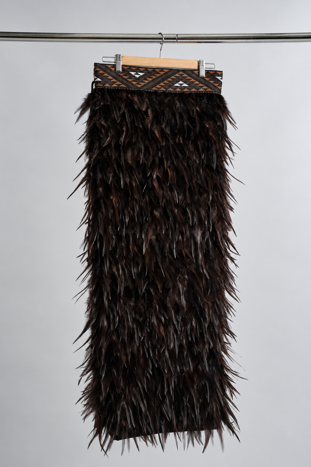Kahu Kiwi full-length korowai hanging front view with chocolate feathers and brown, black and white tāniko band.