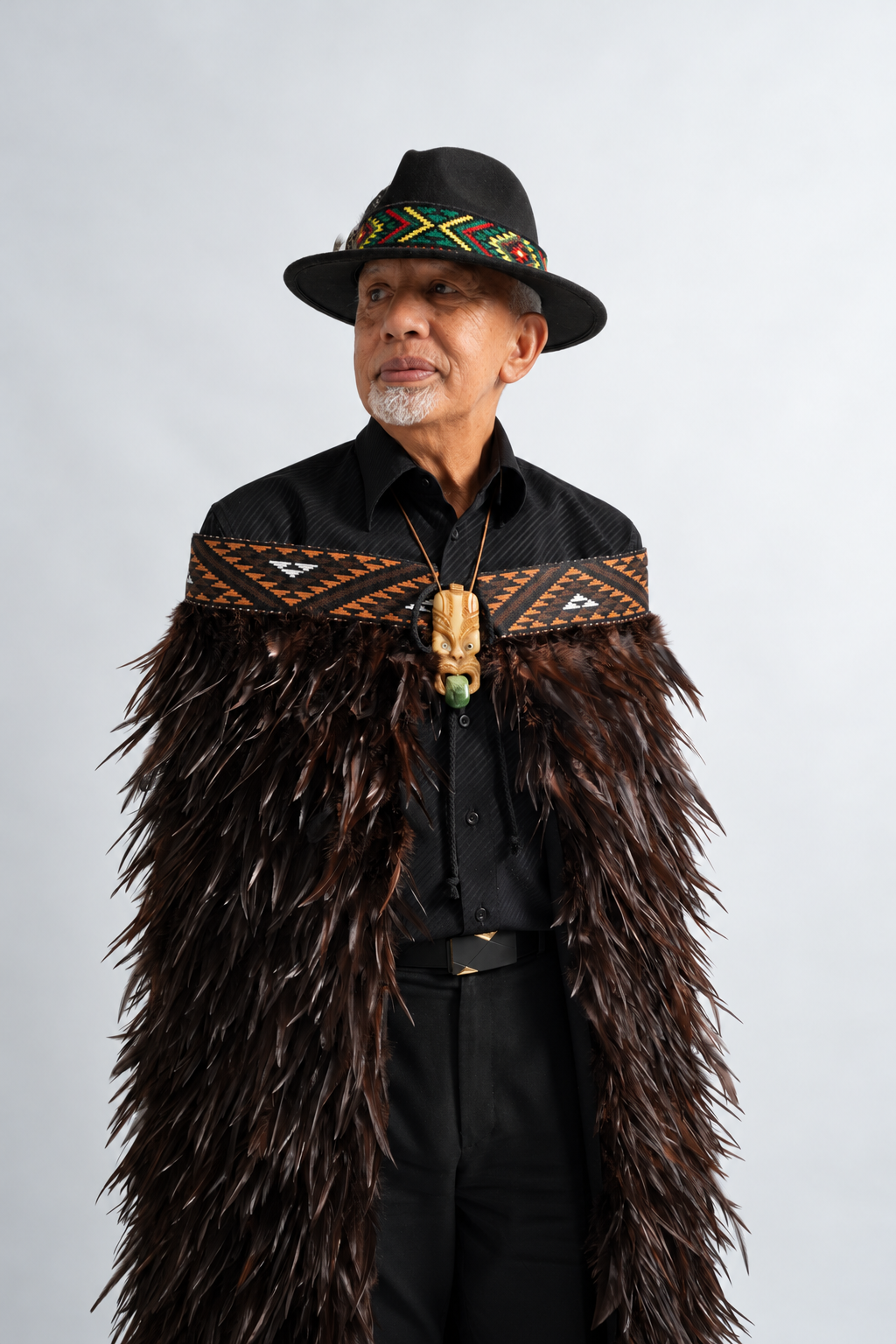 Man wearing Kahu Kiwi korowai with chocolate feathers and brown tāniko band.