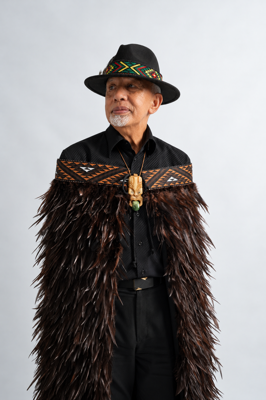 Man wearing Kahu Kiwi korowai with chocolate feathers and brown tāniko band.