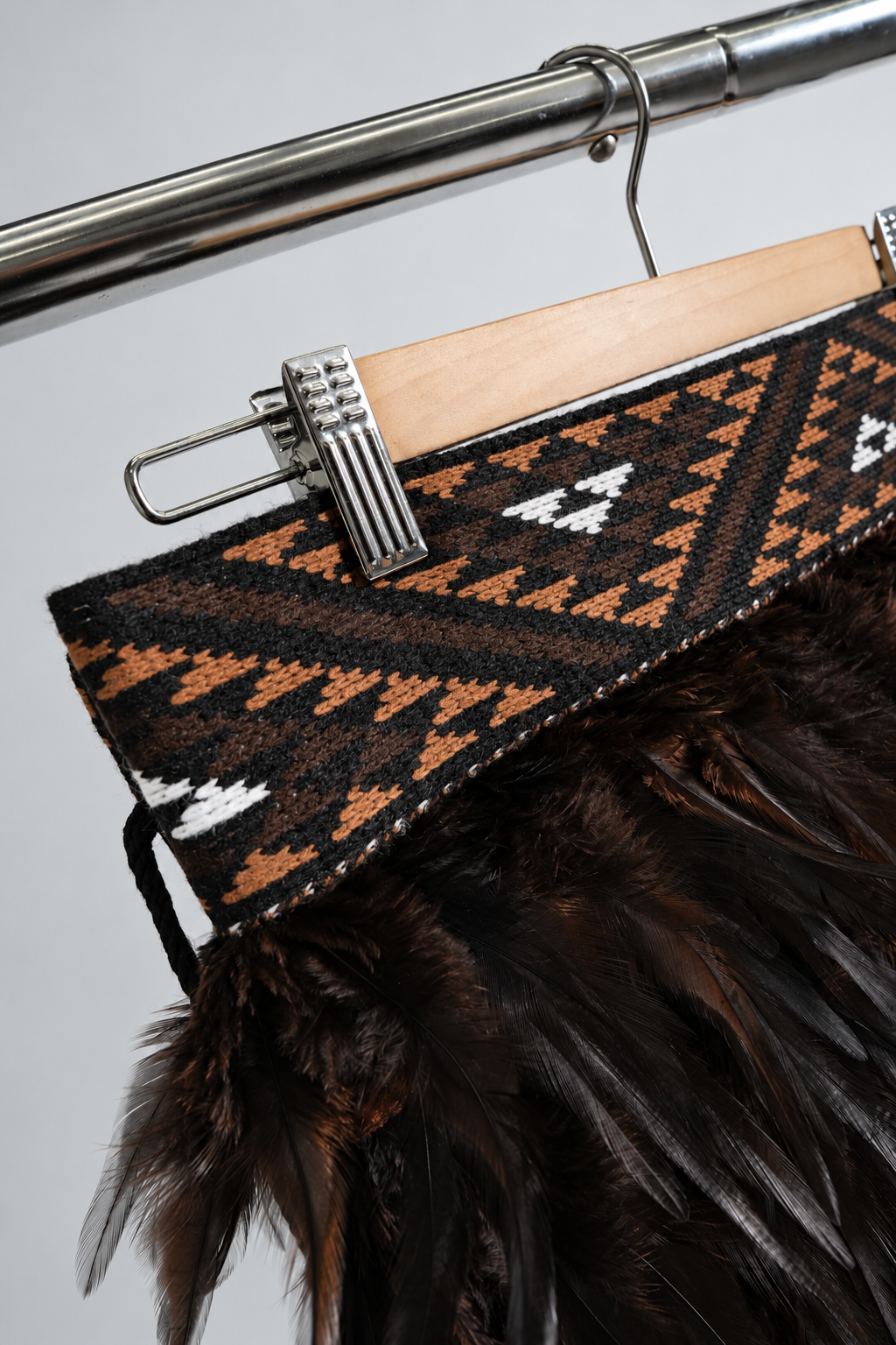 Angled detail of the brown, black and white geometric tāniko band on Kahu Kiwi.
