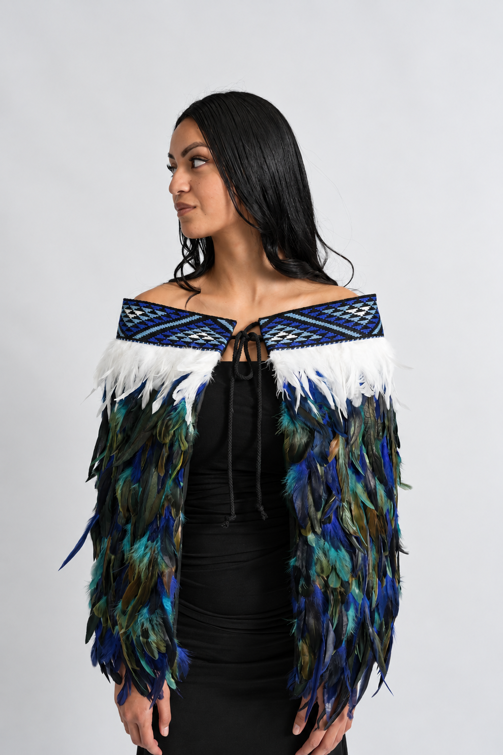 Model wearing the Moana Blue contemporary adult korowai, showing the blue tāniko and feather layers.