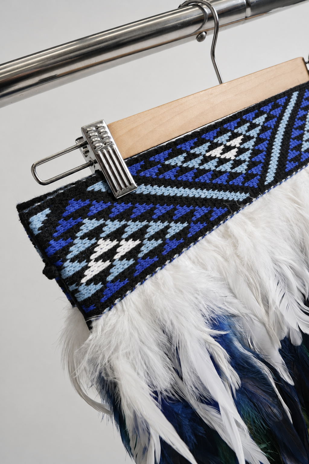 Close-up of the Moana Blue geometric tāniko band and white feather detail.