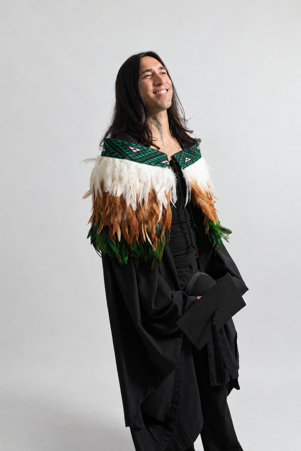 Model smiling while wearing the Ngāhere Green contemporary adult korowai.