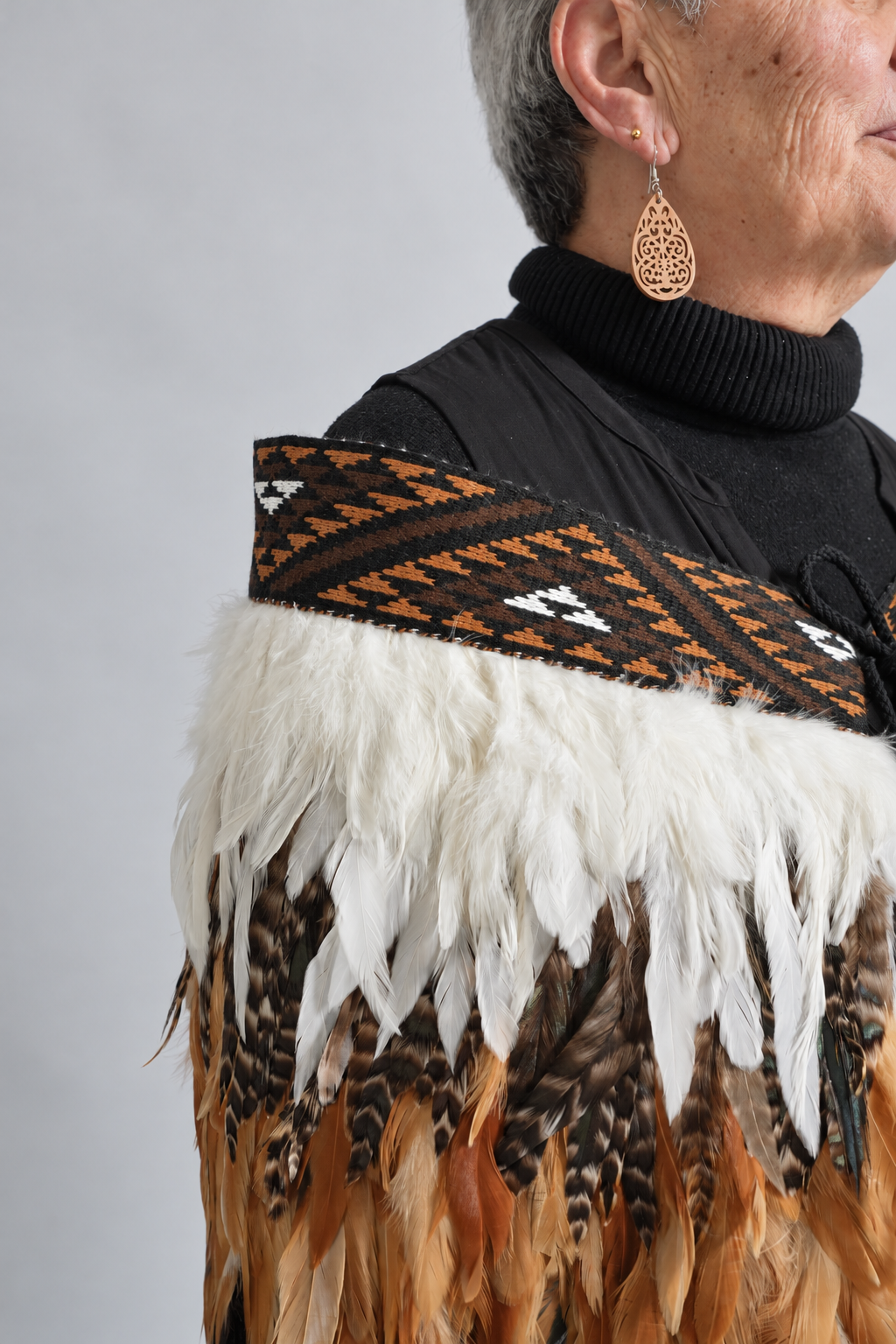 Whenua Brown tāniko, white and striped feather detail worn by a model