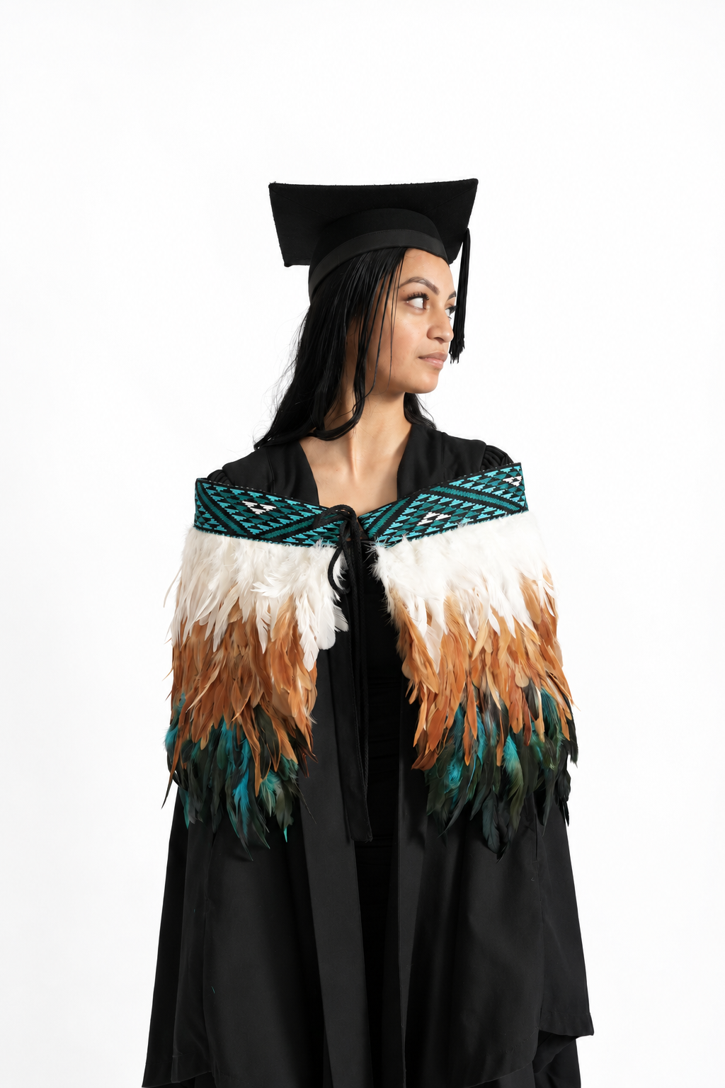 Graduation model wearing Kingfisher Blue adult korowai, looking to the side against a white backdrop.