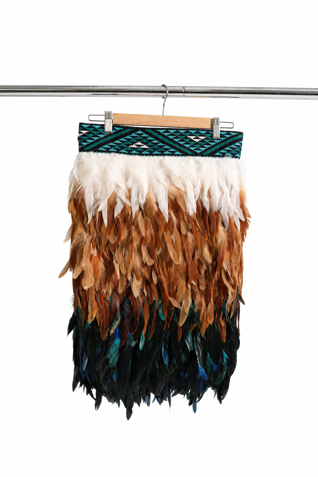 Kingfisher Blue adult Half-length korowai on a wooden hanger, showing the turquoise tāniko band and white, brown, teal and dark feather layers against a white backdrop.