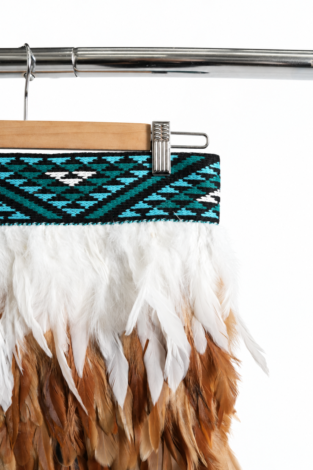 Close-up of the Kingfisher Blue teal, turquoise, black and white tāniko band on a wooden hanger.
