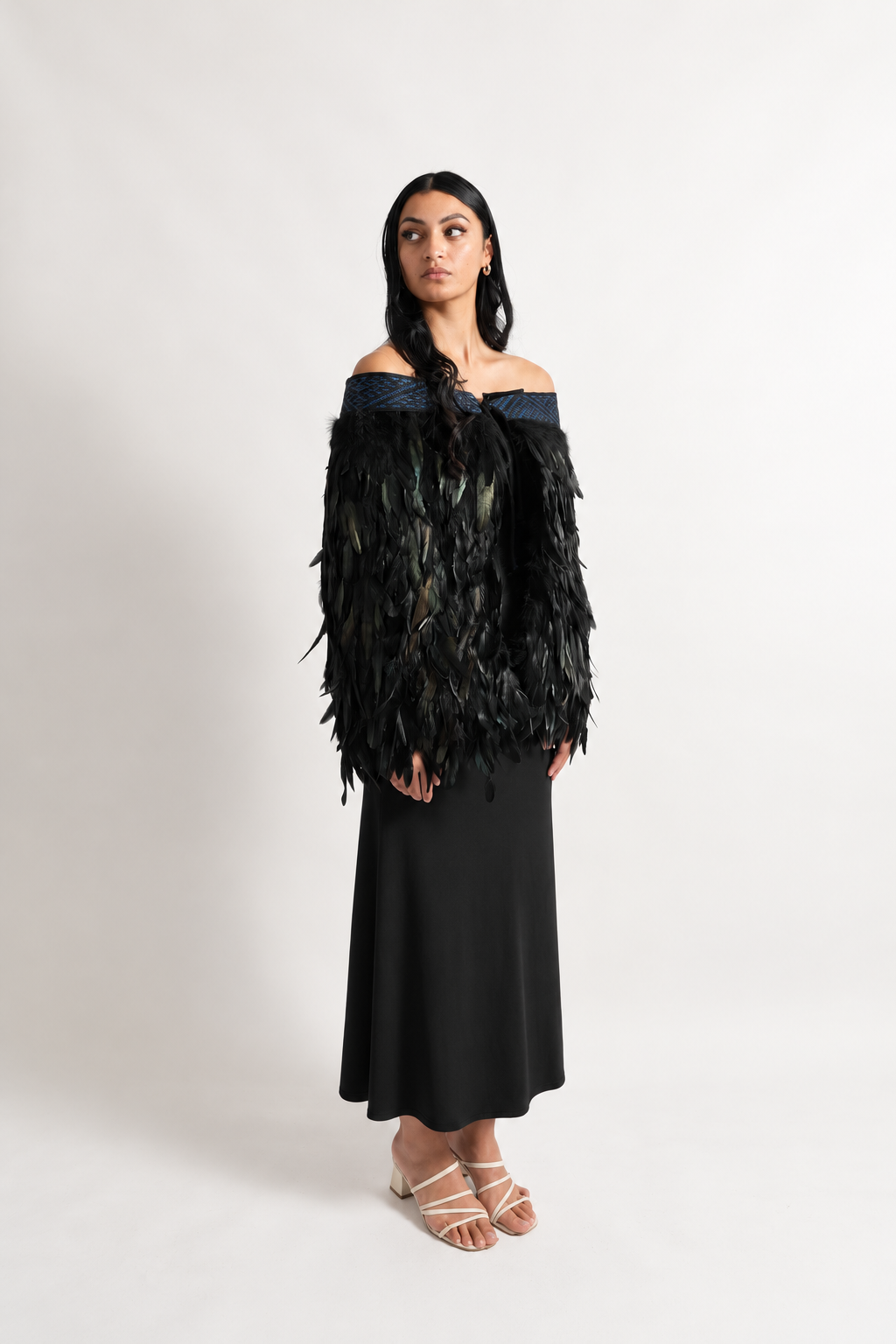 Female model wearing black Pīataata korowai with a pāua blue tāniko band.