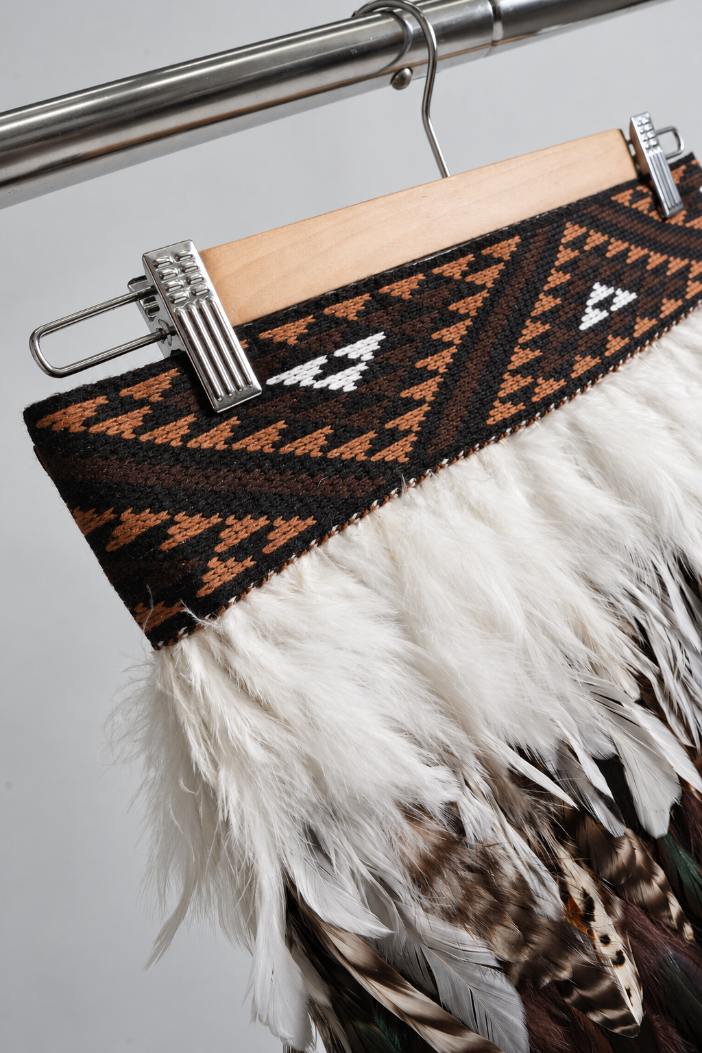 Close-up of Tuku Iho's brown, black and white KBH tāniko band and soft white feathers.